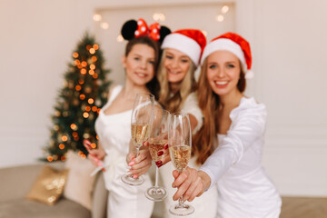 A group of happy cheerful women in elegant outfits having fun laughing drinking champagne celebrating Christmas at a holiday party at home, selective focus
