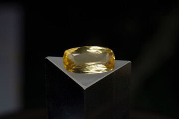 Natural gemstone yellow citrine on a stand on a black background