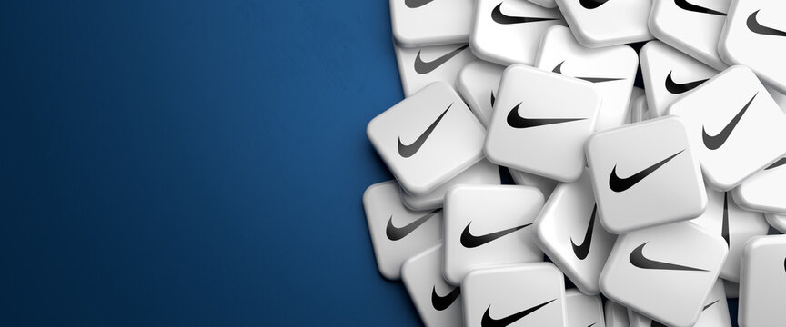 Logos of the sportswear and apparel company Nike Inc. on a heap on a table. Copy space. Web banner format.