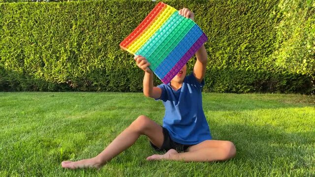 Little boy playing with pop it fidget toy. Popular anti stress toy