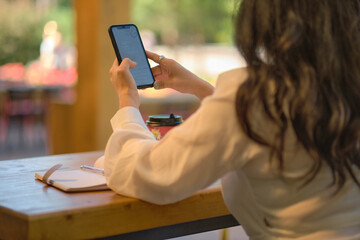 back view Cheerful elegant elderly woman smiling chat with friends on a smartphone.