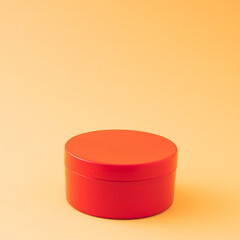 Red round gift box on ocher and orange background with copy space. Advertisement idea. Minimal banner ad concept.