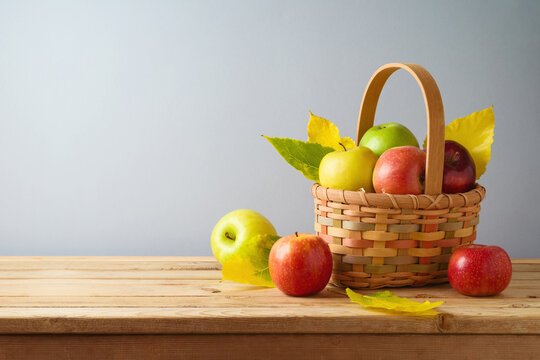 Apples in basket on wooden table. Autumn and fall harvest background