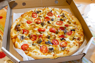 fresh whole pizza with mushrooms, pepperoni sausage and onions in a cardboard pizza box.