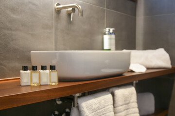 Modern simple bathroom with white bathroom sink standing on wooden shelf and backlit mirror