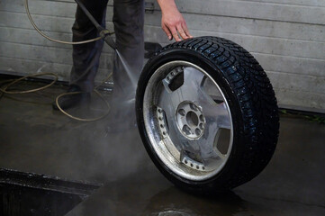 An auto mechanic holds a wheel of a car. Change of car tires according to the season