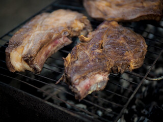 Grilled T-bone steak meat with garlic over the coals on a barbecue, dark background with light of fire.
Crispy crust on a steak