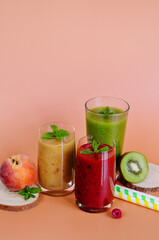 Top view of three different fresh delicious smoothies in a glasses made of peach, banana and berries with mint. Creative concept of healthy detox drink, diet or vegetarian food concept. Copy space.