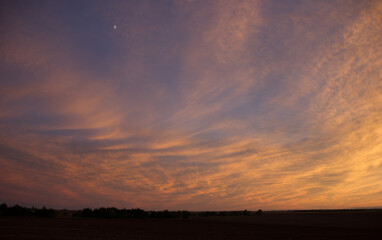 A dramatic orange and purple sunset over an open field