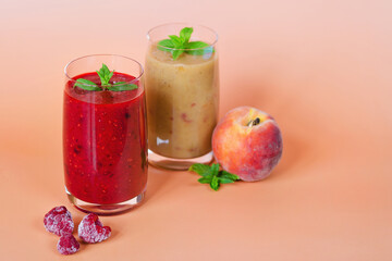 Top view of two different fresh healthy smoothies in a glasses made of peach, banana and berries with mint. Creative concept of healthy detox drink, diet or vegetarian food concept. Copy space.