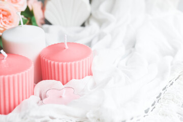 Romantic wedding dating background with pink candles, flowers and white fabric. Soft selective focus. Aromatherapy, beauty, spa, tenderness concept.