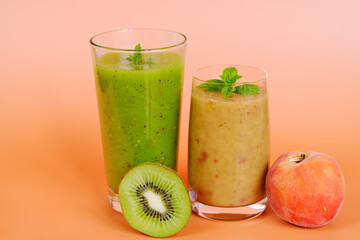 Fototapeta na wymiar Top view of two different fresh healthy smoothies in a glasses made of peach, banana and berries with mint. Creative concept of healthy detox drink, diet or vegetarian food concept. Copy space.