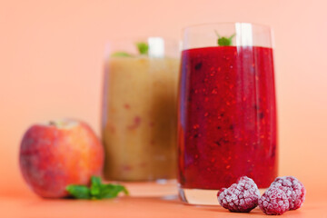 Top view of two different fresh healthy smoothies in a glasses made of peach, banana and berries with mint. Creative concept of healthy detox drink, diet or vegetarian food concept. Copy space.
