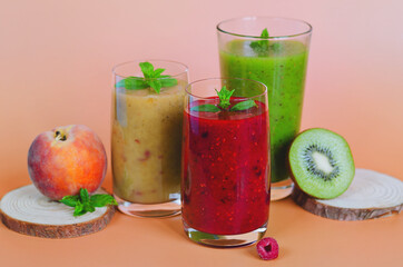 Top view of three different fresh delicious smoothies in a glasses made of peach, banana and berries with mint. Creative concept of healthy detox drink, diet or vegetarian food concept. Copy space.