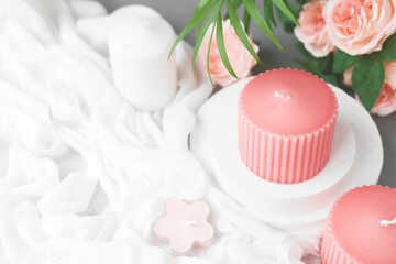 Romantic wedding dating background with pink candles, flowers and white fabric. Soft selective focus. Aromatherapy, beauty, spa, tenderness concept.