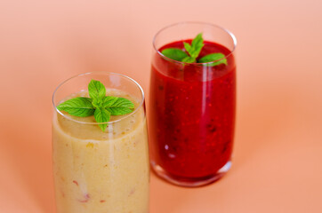 Top view of two different fresh healthy smoothies in a glasses made of peach, banana and berries with mint. Creative concept of healthy detox drink, diet or vegetarian food concept. Copy space.