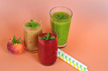 Top view of three different fresh delicious smoothies in a glasses made of peach, banana and berries with mint. Creative concept of healthy detox drink, diet or vegetarian food concept. Copy space.