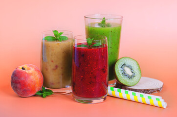 Top view of three different fresh delicious smoothies in a glasses made of peach, banana and berries with mint. Creative concept of healthy detox drink, diet or vegetarian food concept. Copy space.