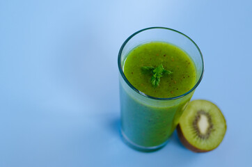 Top view of fresh green healthy smoothie in a glass made of kiwi, chia seeds and banana with mint. Creative concept of healthy detox drink, diet or vegetarian food concept. Copy space.