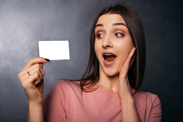 Naklejka premium Woman hold plastic discount credit card shopper beard showing thumb up shocked open mouth european dressed plain t-shirt shopping buyings sales black friday concept copy space mock up 