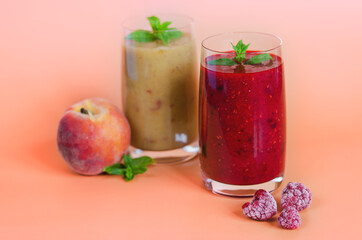 Top view of two different fresh healthy smoothies in a glasses made of peach, banana and berries with mint. Creative concept of healthy detox drink, diet or vegetarian food concept. Copy space.