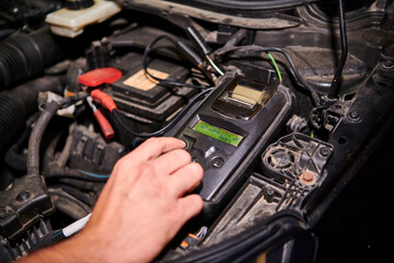Professional Car Mechanic use  Battery Capacity Tester working in auto repair service.