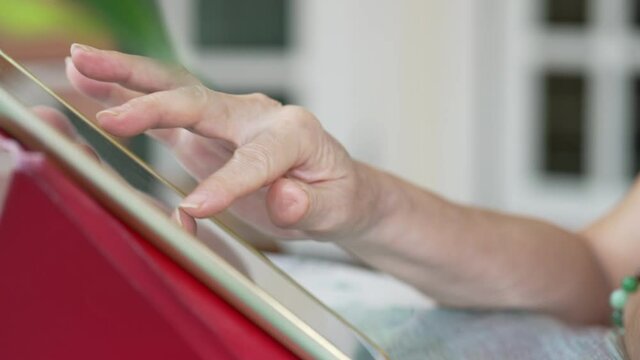 Close Up Hand Of Senior Adult Using Digital Tablet At Home. Technology Concept