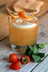 cóctel o cocktail de alcohol con hielo y rodajas de naranja y hierba