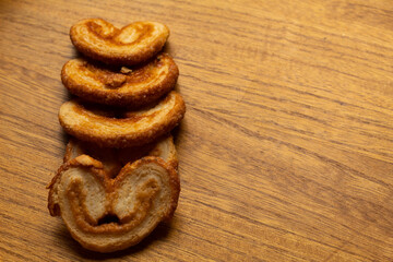 top view of many delicious freshly baked puff pastry ears on a wood colored board