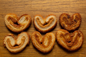top view of many delicious freshly baked puff pastry ears on a wood colored board