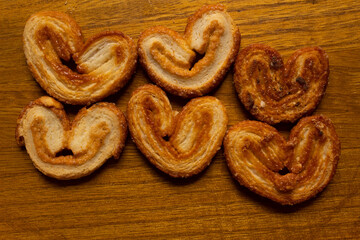 top view of many delicious freshly baked puff pastry ears on a wood colored board