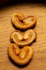 top view of many delicious freshly baked puff pastry ears on a wood colored board