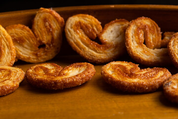 close up of many delicious freshly baked puff pastry ears on a wood colored board