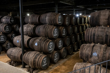 Old porto lodge with rows of oak wooden casks for slow aging of fortified ruby or tawny porto wine in Vila Nova de Gaia, Portugal
