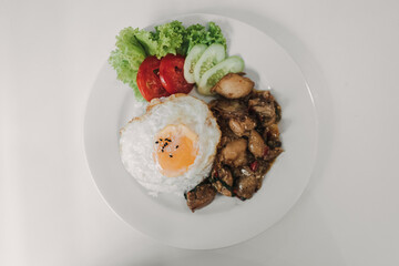 Rice with Basil Fried Chicken and fried egg served on white table.
