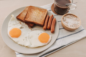 Easy breakfast set of fried eggs toasted bread sausages and tuna spread.