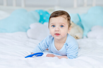 baby boy with a rodent for teething or a rattle on the bed for sleeping, healthy happy little baby...