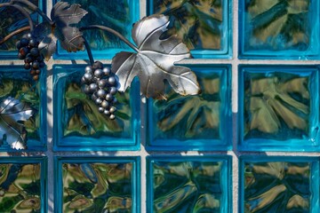 Motyw metalowych winogron i niebieska luksfera jako dekoracja w jednym z ogrodów botanicznych - obrazy, fototapety, plakaty
