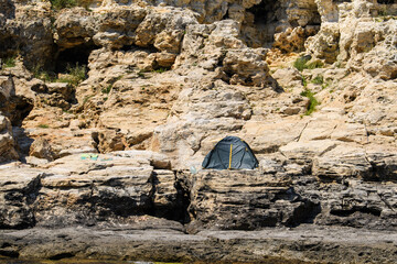 The lonely tent of the traveler stands on the rocky seashore.