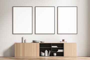 Three framed posters in the light beige waiting room with sideboard