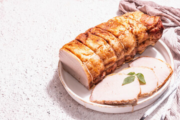 Baked pork loin on a ceramic stand with cutlery