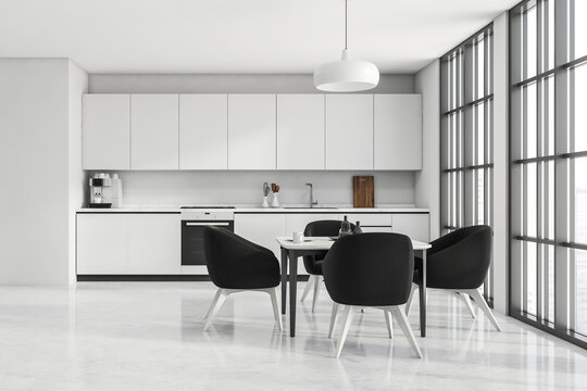 White kitchen space with panoramic windows and black armchairs
