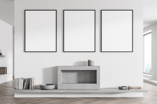 Three posters on the white and grey living room wall with fireplace