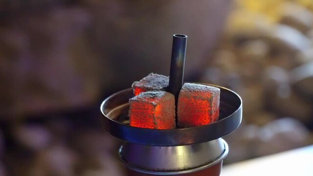 Close-up of burning embers on hookah. Media. Square red coals ignite when hookah is inflated. Red coals burn on hookah sup. 