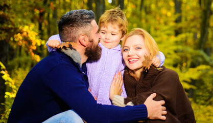 Mother, father and son on autumn walk in park. Happy family. Parents and child relaxing together in sunny day.