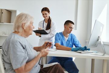 a nurse and a doctor see an elderly patient in a medical office