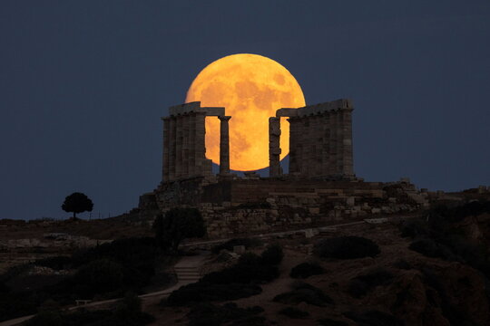 An almost full moon rises over the Temple of Poseidon in Cape Sounion, near Athens