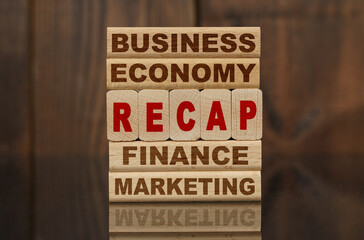 Wooden blocks with the text - Business, Economy, Finance, Marketing and RECAP