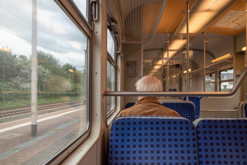 Interior and selected focus view at the back of elder male passenger with face protection mask and skinhead who sit in tram or train in Germany.