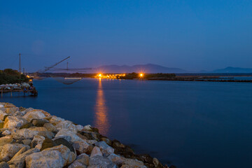 After sunset at the port of Marina di Pisa in summer . Sea and fishing rigs